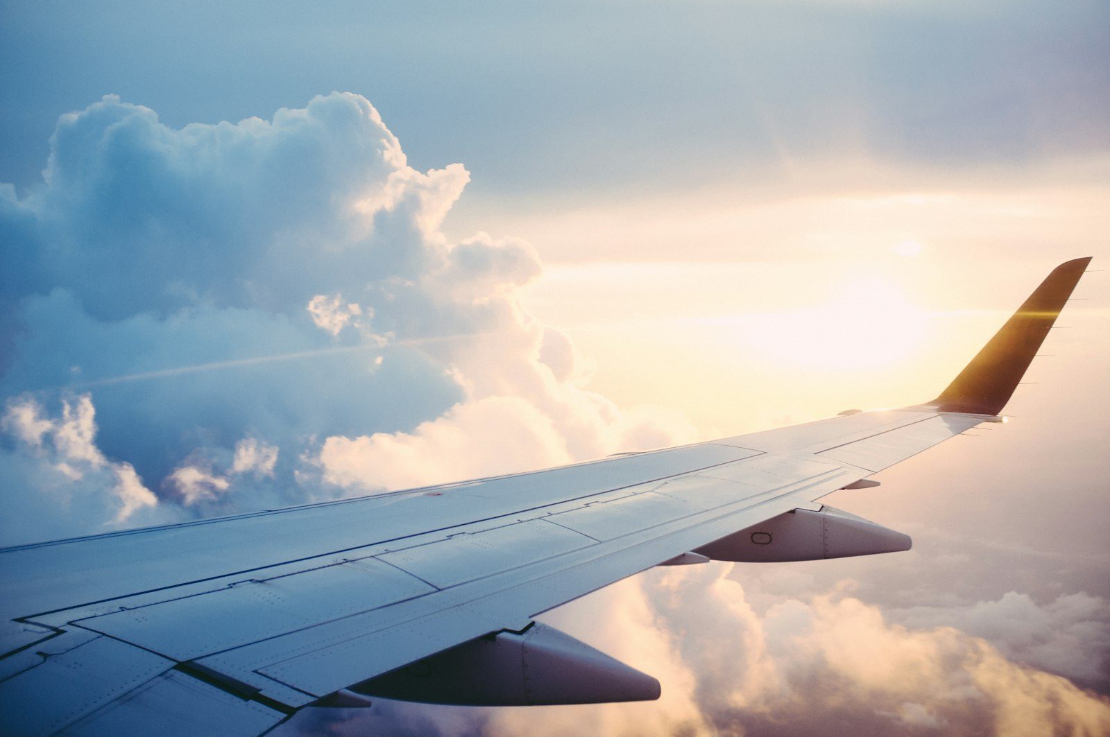 Asa do avião sobrevoando nuvens ao entardecer